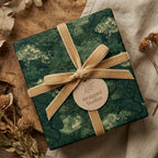 Luxury forest green wrapping paper by Wrapped Studios with a gold velvet ribbon on rustic wood.
