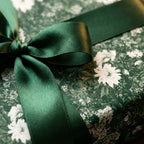 Elegant dark green floral wrapping paper with green satin bow, luxury gift wrap by Wrapped Studios.