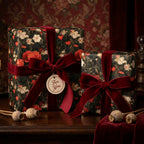 Moody dark floral wrapping paper with red velvet bows on luxury gift boxes by Wrapped Studios.