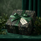 Luxury dark botanical wrapping paper with a forest green ribbon and Wrapped Studios tag.