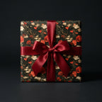 Luxury dark floral wrapping paper with red hearts and a satin bow on a gift box by Wrapped Studios.