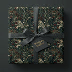 Dark botanical wrapping paper with a black satin bow on a luxury gift box by Wrapped Studios.