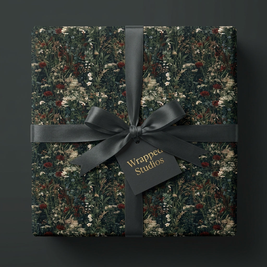 Dark botanical wrapping paper with a black satin bow on a luxury gift box by Wrapped Studios.