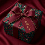 Luxury floral wrapping paper on a box with burgundy ribbon bow and tag on red silk by Wrapped Studios.