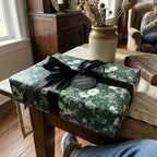 Vintage green floral wrapping paper with a black satin ribbon on a gift box by Wrapped Studios.