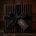 Elegant gift box wrapped in striped wrapping paper with a velvet bow and "For Him" tag.