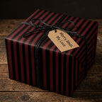 Striped Christmas gift wrap in red and black with twine and a tag that reads "Merry Xmas My Love."