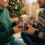 Couple exchanging Christmas gifts wrapped in black cat-themed holiday wrapping paper with red ribbon.