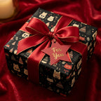 Black Christmas gift wrapped in cat-themed wrapping paper with a red satin ribbon and "For You" tag.