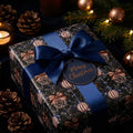 Luxury Christmas wrapping paper with pinecones, navy blue satin bow, and gift tag by Wrapped Studios.