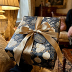 Luxury Christmas gift wrap with elegant navy blue floral pattern and gold bow by Wrapped Studios.