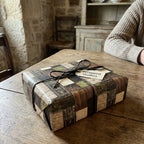 Vintage rustic wrapping paper on a gift box tied with black twine, by Wrapped Studios.