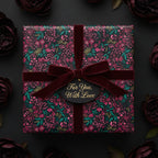 Elegant floral wrapping paper in deep burgundy and green, tied with a velvet ribbon and "For You, With Love" tag.