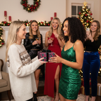 Woman gives floral birthday wrapping paper gift box with black ribbon to friend at festive Christmas party.