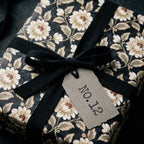 Luxury vintage floral wrapping paper by Wrapped Studios on a gift box with a black ribbon.