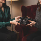 Exchanging gift wrapped in elegant floral wrapping paper with a black ribbon bow.