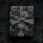 Elegant black floral wrapping paper with gray ribbon and gift tag.