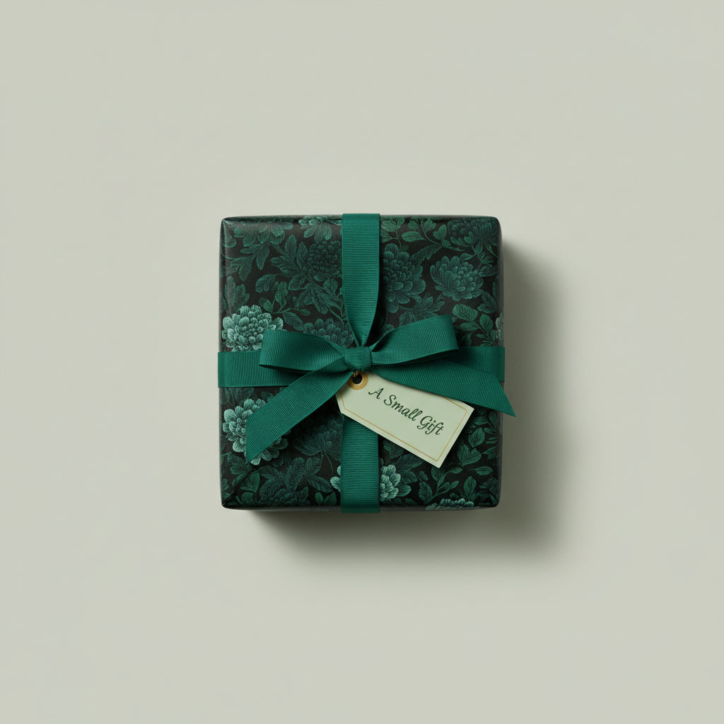 Square gift box wrapped in elegant dark green floral wrapping paper with matching ribbon and gift tag.