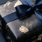 Luxury dark floral wrapping paper with cream flowers and navy satin ribbon by Wrapped Studios.