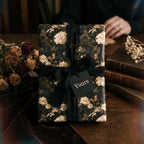 Dark vintage floral wrapping paper with black silk ribbon on a luxury gift box by Wrapped Studios.