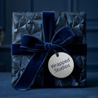 Luxury navy blue geometric wrapping paper with a velvet bow and silver gift tag by Wrapped Studios.