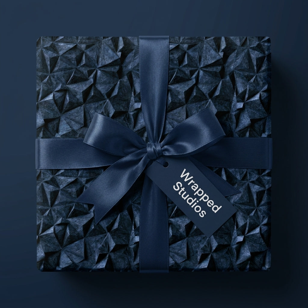 Luxury navy blue geometric wrapping paper with a satin bow and tag by Wrapped Studios.