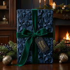 Luxury navy blue geometric Christmas wrapping paper with a green velvet bow by Wrapped Studios.