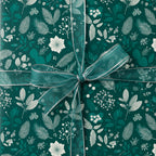Elegant gift wrapped in dark green floral wrapping paper with a sheer ribbon and bow.