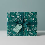 Elegant gift box wrapped in green floral wrapping paper with teal ribbon and a "special delivery" tag.