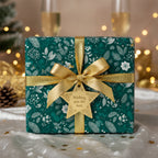 Elegant gift wrapped in green floral wrapping paper with gold ribbon and star tag for Christmas.