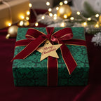 Elegant Christmas gift wrap with green floral pattern, velvet ribbon, and "Merry Christmas" tag.