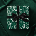 Elegant gift wrapped in green floral wrapping paper with black velvet ribbon, perfect for Christmas or a birthday.