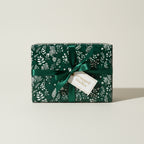 Elegant gift wrapped in dark green floral wrapping paper with a satin ribbon and gift tag.