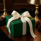 Elegant dark green gift wrapped in solid color paper with cream ribbon bow, ideal for Christmas or birthdays.