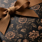 Luxury black and gold floral wrapping paper with a bronze ribbon bow, elegant gift wrap by Wrapped Studios.