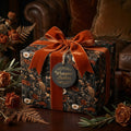 Vintage dark floral wrapping paper with a burnt orange velvet bow on a gift box by Wrapped Studios.