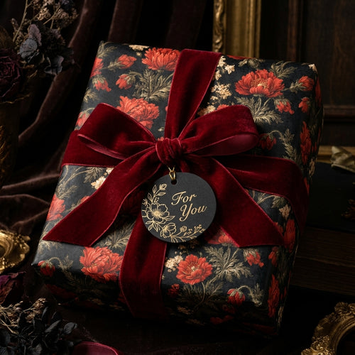 Luxury dark floral wrapping paper on a gift box with a red velvet bow by Wrapped Studios.