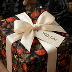 Dark luxury floral wrapping paper with a cream satin bow and 'With Love' tag by Wrapped Studios.