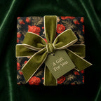 Vintage floral wrapping paper with red flowers and green velvet bow, luxury gift wrap by Wrapped Studios.