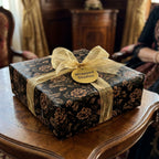 Vintage black and gold floral wrapping paper with sheer gold bow on a gift box, luxury gift wrap by Wrapped Studios.