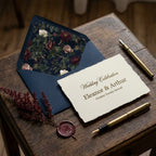 Vintage moody floral envelope liner and wedding invitation on a rustic wood table by Wrapped Studios.