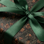 Luxury forest Christmas gift wrap with pinecones and a green satin ribbon by Wrapped Studios.