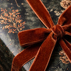 Luxury Christmas gift wrap with pinecone print and a rust velvet ribbon bow by Wrapped Studios.
