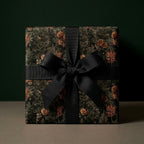 Luxury Christmas wrapping paper with a moody forest pinecone print and black bow by Wrapped Studios.