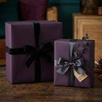 Elegant gifts wrapped in plum paper with black velvet & satin ribbon, perfect for luxurious celebrations.
