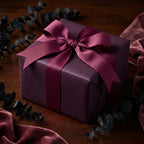 Elegant plum wrapping paper with satin ribbon bow on wood table.