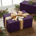 Elegant plum purple wrapping paper on a gift box with a gold ribbon and holiday greenery.