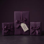 Elegant eggplant purple gift wrap on presents with ribbon bows; solid color wrapping paper for birthdays, weddings, or holidays.