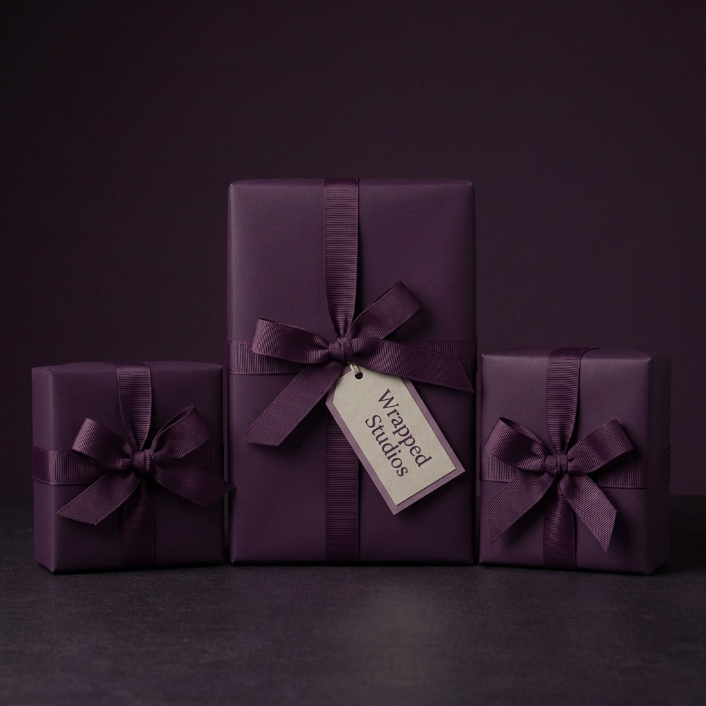 Elegant eggplant purple gift wrap on presents with ribbon bows; solid color wrapping paper for birthdays, weddings, or holidays.