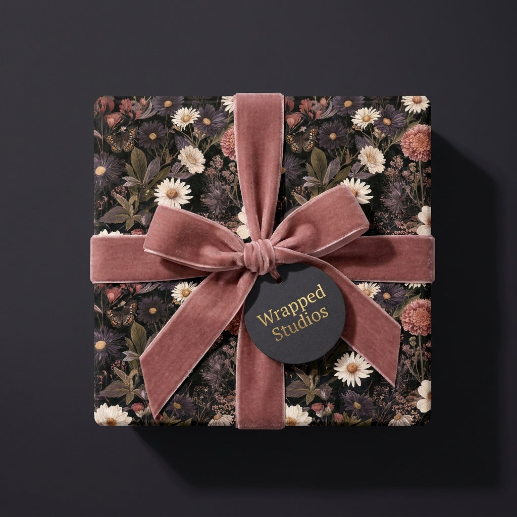 Luxury dark floral wrapping paper with a dusty pink velvet ribbon bow on a gift box by Wrapped Studios.